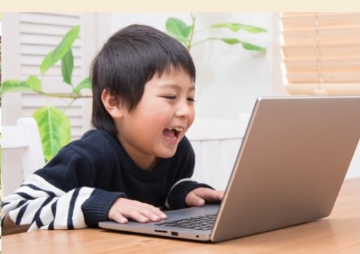 ノートパソコンで遊ぶ笑顔の幼児